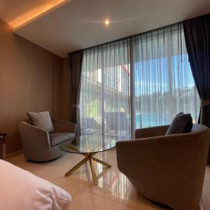 een hotelkamer met 2 stoelen en een glazen tafel bij The TJ Hotel Jomtien in Jomtien Beach