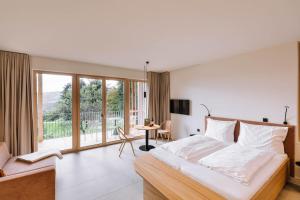 a bedroom with a bed and a table and a balcony at SCHILCHERLANDLEBEN - Hochgrail in Greisdorf