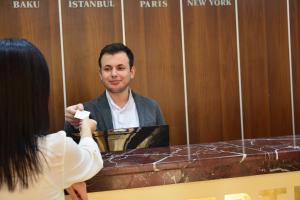 uma mulher a tirar uma fotografia a um homem sentado à mesa em Ariva Hotel and Spa em Baku