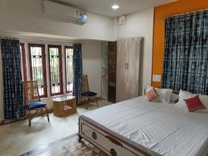 a bedroom with a large bed and two chairs at Mulberry Guesthouse in Guwahati