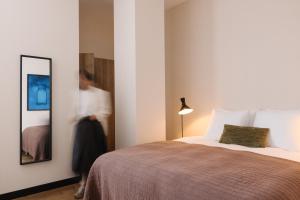 Una mujer está de pie junto a una cama en una habitación en Plesman Residences en Scheveningen