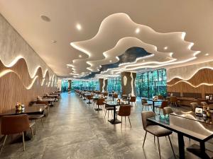 een restaurant met tafels en stoelen en een groot plafond bij The TJ Hotel Jomtien in Jomtien Beach