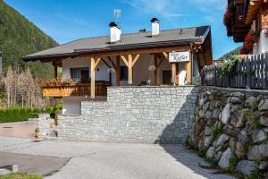 a house with a stone wall and a fence at Haus Kofler in Racines