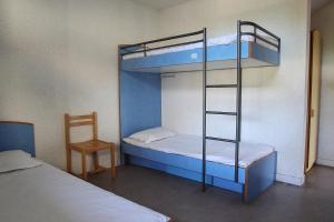 two bunk beds in a room with a chair and a ladder at Auberge de Jeunesse HI Genêts in Genêts