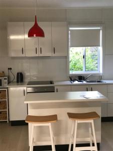 a kitchen with a white counter and two stools at Sinclair Cottage in Port Lincoln