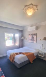 a bedroom with a large white bed and a window at Moruya Monarch Hotel in Moruya
