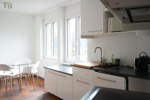 uma cozinha com armários brancos e uma mesa e cadeiras em Gartenwohnung vor den Toren Berns em Zollikofen