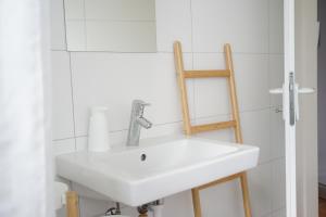um lavatório branco na casa de banho com uma escada de madeira em Gartenwohnung vor den Toren Berns em Zollikofen
