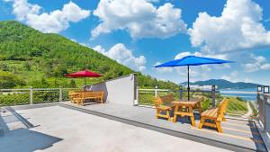 eine Terrasse mit 2 Stühlen, einem Tisch und einem Sonnenschirm in der Unterkunft Paran Pension in Yeosu