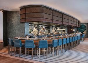 ein Restaurant mit einer langen Bar mit blauen Stühlen in der Unterkunft Four Seasons Hotel London at Park Lane in London