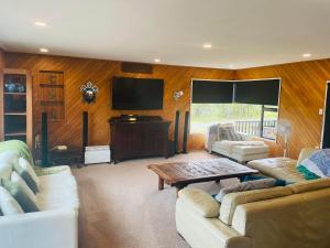ein Wohnzimmer mit 2 Sofas und einem Flachbild-TV in der Unterkunft Te Papatapu Retreat in Raglan