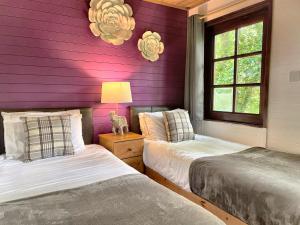 duas camas num quarto com paredes roxas em Woodland Lodge’s St Clears em Carmarthen