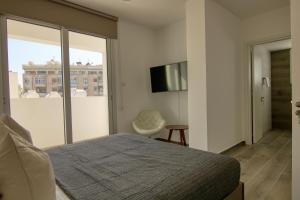 - une chambre avec un lit, une télévision et une fenêtre dans l'établissement Phaedrus Living Coral Suites Aquatic, à Larnaka