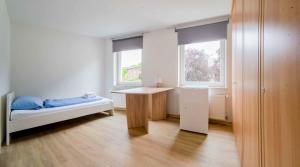 um quarto com uma cama, uma secretária e 2 janelas em Ferienwohnung Kaufmann 3 em Rabenkirchen-Faulück