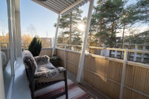 a rocking chair on a balcony with a view of trees at Nordic Gem near railway station, free parking and wifi in Rovaniemi