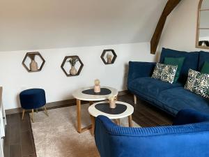 ein Wohnzimmer mit 2 blauen Sofas und 2 Tischen in der Unterkunft Cense au Bois in Saint-Amand-les-Eaux