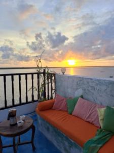 a couch sitting on a balcony with a sunset at Pwani House - Lamu Seafront in Lamu