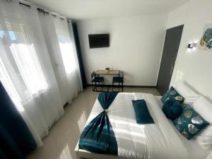 a bedroom with a large white bed with blue pillows at Appartement T4 Cosi: TV Netflix Parking in Montélimar