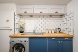 a kitchen with blue cabinets and a washing machine at The Riverside Hideaway - Stockbridge in Edinburgh