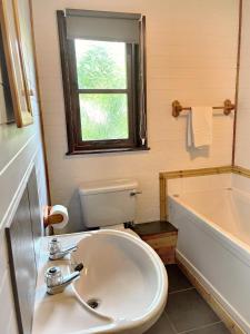 a bathroom with a sink and a toilet and a window at Woodland Lodge’s St Clears in Carmarthen