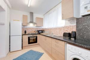 a kitchen with a white refrigerator and a dishwasher at Lovely 3bed split level flat with outside space in London