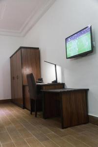 ein Büro mit einem Schreibtisch und einem TV an der Wand in der Unterkunft Mosaly Residence Caboma in Cotonou