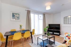 a living room with a dining room table and yellow chairs at Lovely 3bed split level flat with outside space in London