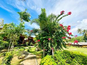 a garden with a palm tree with red flowers at Baan Check In in Ko Lanta