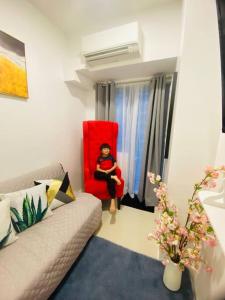 una mujer sentada en una silla roja en una sala de estar en Lovely Fame@5SYu, en Manila