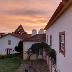 a white house with a sunset in the background at quinta do outeiro in Vila Nova de Poiares