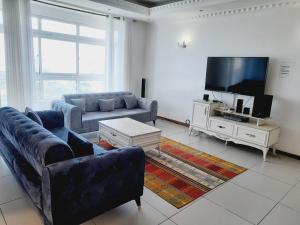 Perfect sea view 2 في مومباسا: غرفة معيشة مع أريكة وتلفزيون بشاشة مسطحة