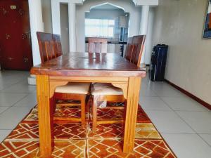 Perfect sea view 2 في مومباسا: طاولة خشبية بأربعة كراسي ومطبخ