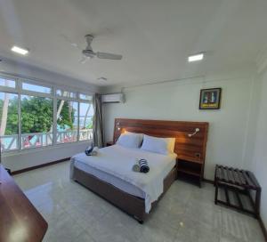 een slaapkamer met een groot bed en een groot raam bij Batuta Maldives Surf View in Thulusdhoo
