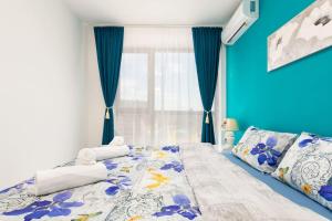 a bedroom with a bed with blue walls and a window at Comfy Apartment with Private Parking in Plovdiv