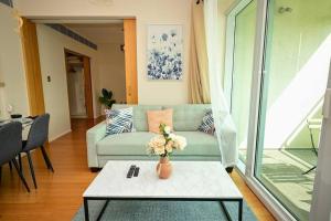 a living room with a couch and a table with flowers at Starlight 1BR Apartment: Retreat for Your Getaway in Abu Dhabi