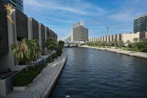 a river in a city with buildings and palm trees at Starlight 1BR Apartment: Retreat for Your Getaway in Abu Dhabi