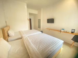 a bedroom with two beds and a tv on the wall at Urbanview Hotel Medio Inn Palu by RedDoorz in Palu