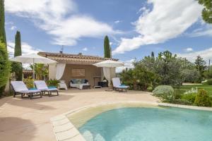 a swimming pool in a yard with chairs and umbrellas at Villa Ambre in Digne-les-Bains