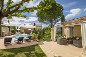 a backyard with a pool and patio furniture and umbrellas at Villa Ambre in Digne-les-Bains