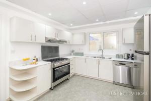 a white kitchen with white cabinets and a sink at LUX The Meadows 5 Bed Villa in Dubai