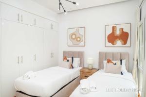 Duas camas num quarto com paredes brancas em LUX The Meadows 5 Bed Villa em Dubai