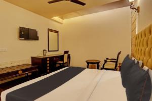 a bedroom with a bed and a desk and a television at Townhouse The Royce New Friends Colony in New Delhi
