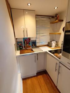 a small kitchen with white cabinets and a wooden floor at Little Oak - Double (Kingsize) Self Contained Oak Studio - Sleeps 2 in Chiddingfold