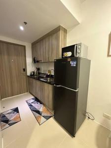 a kitchen with a black refrigerator and wooden cabinets at Lovely Fame7Roses in Manila