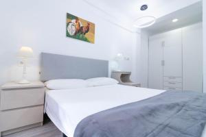 a white bedroom with a large bed and a lamp at Piso en el Centro de Zaragoza, Parking GRATIS, Check-in 24h in Zaragoza