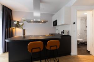 a kitchen with a black counter and two stools at The Doorman Goethe Frankfurt am Main in Frankfurt/Main
