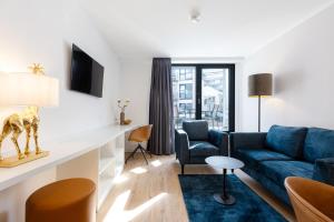 a living room with a blue couch and a chair at The Doorman Goethe Frankfurt am Main in Frankfurt