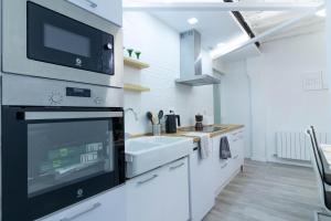 a white kitchen with a sink and a microwave at Piso reformado en el centro histórico PARKING GRATIS Check-in 24 h in Zaragoza