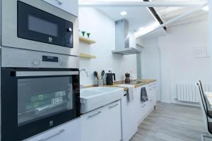 a white kitchen with a sink and a microwave at Piso en el Centro de Zaragoza, Parking GRATIS, Check-in 24h in Zaragoza