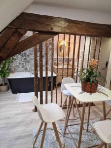 Zimmer mit einem Tisch, Stühlen und einer Badewanne in der Unterkunft Appartement cocooning in Solre-le-Château